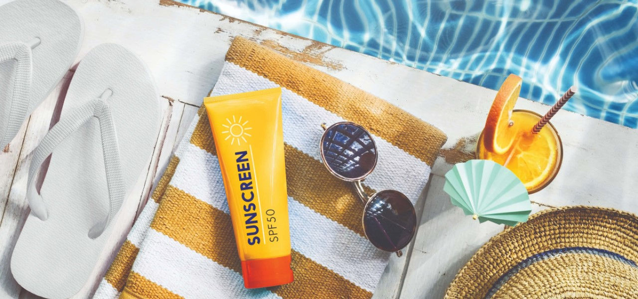 flip flops, sunscreen, and towel by pool